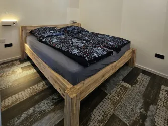 Ein gemütliches Schlafzimmer mit einem Holzbett. Der moderne Bodenbelag ergänzt die entspannende Atmosphäre.
