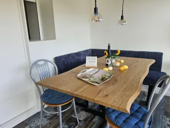 Ein einladender Essbereich mit einem modernen Holztisch, gemütlichen Stühlen und einer blauen Bank.