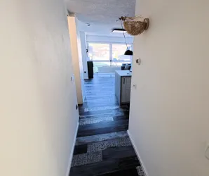 Ein heller Flur mit einem modernen Bodenbelag. Im Hintergrund ist ein gemütlicher Wohnbereich zu sehen.