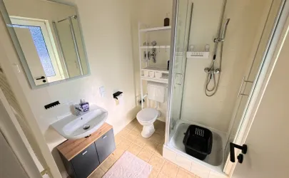 Ein modernes Badezimmer mit Dusche, Toilette und Waschbecken. Helle Farben und ein praktischer Stauraum sorgen für eine angenehme Atmosphäre.