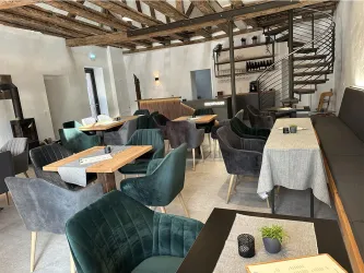 Ein modernes Restaurant mit stilvollen Möbeln und einer einladenden Atmosphäre. Die Einrichtung besteht aus bequemen Stühlen und Holztischen unter einem rustikalen Holzdach.