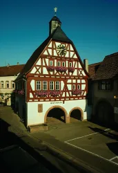 Ein historisches Rathaus im Fachwerkstil mit Blumen vor den Fenstern. Der Himmel ist blau und klar.