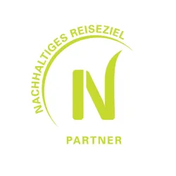 Ein Logo mit dem Text "Nachhaltiges Reiseziel" und "Partner". Es ist in leuchtendem Grün auf weißem Hintergrund gestaltet.