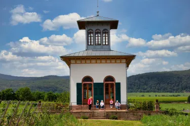 Ein hübsches Gebäude mit einem Turm steht inmitten eines grünen Weinbergs. Die Wolken am blauen Himmel verleihen der Szene eine friedliche Atmosphäre.