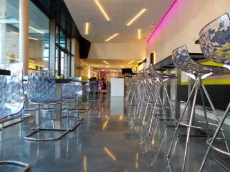 Eine moderne Bar mit transparenten Stühlen und einem glänzenden Boden. Die Beleuchtung sorgt für eine stilvolle Atmosphäre.