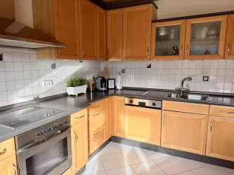 Voll ausgestattete Küche mit modernen Geräten, großzügiger Arbeitsfläche und hellen Holzfronten – ideal zum komfortablen Kochen während des Aufenthalts.