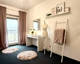 Ein elegantes Zimmer mit einem Schminktisch, einem Spiegelschrank und einer Schneiderpuppe. Weiche Teppiche und Vorhänge in sanften Farben verleihen dem Raum eine gemütliche Atmosphäre.