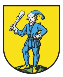 Ein Wappen mit einem Mann in blauem Gewand und einer Mütze, der einen Knochen in der Hand hält. Der Hintergrund ist gelb und der Mann steht auf einem grünen Hügel.