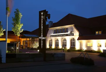 Das Gebäude der Winzergenossenschaft in Kallstadt vo Außen und am Abend, mit schöner Beleuchtung.