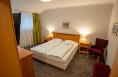 Doppelzimmer mit Blick auf ein Doppelbett, Fenster und 2 Sessel