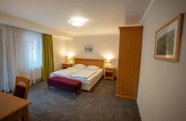 <p>Doppelzimmer mit Blick auf ein Doppelbett, Schrank und eine Fußbank am Bettende
