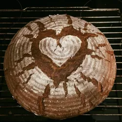 Ein frisch gebackenes Brot mit einem Herzmuster auf der Oberfläche. Das Brot hat eine rustikale Farbe und eine schöne Textur.