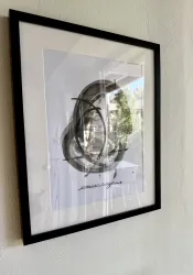 Ein gerahmtes Kunstwerk an einer Wand. Es zeigt eine abstrakte Zeichnung mit geschwungenen Linien und einer Unterschrift darunter.