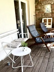Ein gemütlicher Balkon mit zwei Loungesesseln und einem kleinen Tisch. Auf dem Tisch steht eine Pflanze in einem dekorativen Topf.