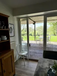 Ein heller Raum mit einem Blick auf eine Terrasse und einen grünen Garten. Die Fenster lassen viel Licht herein und schaffen eine einladende Atmosphäre.