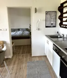 Eine moderne Küche mit einem kleinen Essbereich und Blick auf ein Schlafzimmer. Der Raum ist hell und freundlich gestaltet.