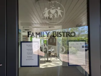 Ein einladendes Bistro mit dem Namen „Family Bistro“. Durch die Glastür sind Tische und eine helle, freundliche Atmosphäre sichtbar.