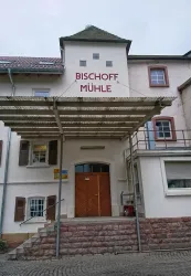 Ein historisches Gebäude mit der Beschriftung "BISCHOFF MÜHLE". Es hat eine interessante Architektur und einen einladenden Eingang.