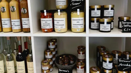 Ein Regal mit verschiedenen Gläsern und Flaschen. Die Produkte umfassen Säfte, Marmeladen und andere Spezialitäten.