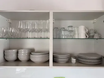 Ein gut organisierter Küchenschrank mit Gläsern, Tellern und Schüsseln. Die Geschirrteile sind sauber und ordentlich angeordnet.