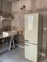 Eine helle Küche mit einem retro Kühlschrank und einer Spüle. Die Wände sind rustikal gestaltet und aus Holz.