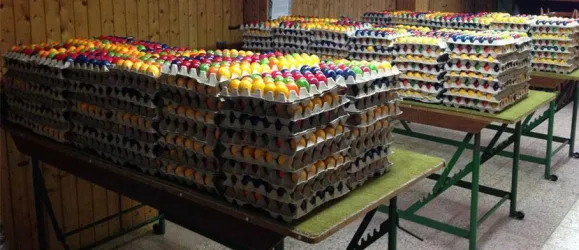 Eine große Anzahl von Eierkartons ist auf Tischen gestapelt. Die Eier sind in verschiedenen Farben und Anordnungen.