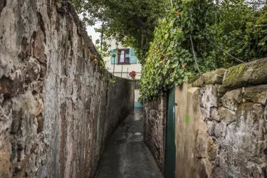 Eine malerische Straße mit bunten Häusern und Blumen. Girlanden schmücken die Gebäude und schaffen eine festliche Atmosphäre.