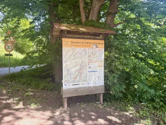 Ein Orientierungsschild für Wanderer im Wald. Es zeigt Wanderwege und Informationen über die Umgebung.