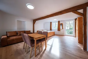 Ein gemütliches Wohnzimmer mit einem Essbereich und einer kleinen Terrasse. Der Raum hat einen hellen, modernen Stil mit Holzdetails.