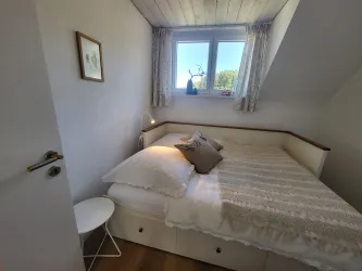 Ein gemütliches Schlafzimmer mit einem großen Bett und einem Fenster, das auf eine grüne Landschaft blickt.