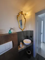 Ein modernes Badezimmer mit einer eleganten goldenen Spiegelrahmung. Die Einrichtung ist schlicht und geschmackvoll mit einem runden Waschbecken.