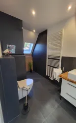 Ein modernes Badezimmer mit einer eleganten Toilette und einem Waschbecken. Die Wände sind in neutralen Farben gehalten, und es gibt eine moderne Handtuchheizung.