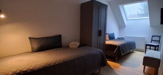 Ein gemütliches Schlafzimmer mit zwei Einzelbetten und einem Kleiderschrank. Das Zimmer hat eine helle Fensterfront und eine einladende Atmosphäre.