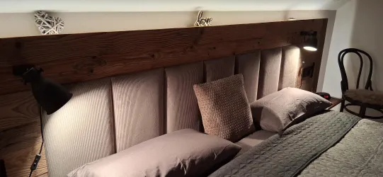 Ein stilvolles Schlafzimmer mit einem gepolsterten Kopfteil und bequemen Kissen. Sanfte Beleuchtung sorgt für eine entspannte Atmosphäre.