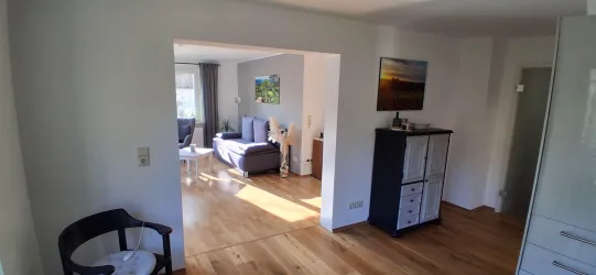 Ein helles Wohnzimmer mit einem gemütlichen Sofa und einem Couchtisch. Der Raum ist gut beleuchtet und hat einen schönen Holzboden.