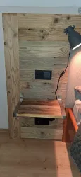 Ein Holz-Nachttisch mit integriertem Stromanschluss und einem Leselicht. Die rustikale Optik sorgt für eine gemütliche Atmosphäre.