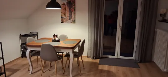 Ein eleganter Essbereich mit einem Tisch und vier Stühlen. Große Fenstertüren bringen etwas Licht in den Raum.