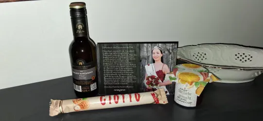 Ein Stillleben mit einem Flasche Öl, einer Verpackung mit Süßigkeiten und einem Joghurtbecher. Dazu ein Bild und ein Text, die zusammen eine besondere Gelegenheit feiern.