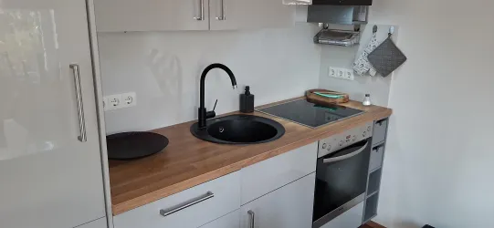 Eine moderne Küche mit Holzarbeitsplatte und schwarzen Armaturen. Die Ausstattung umfasst ein Spülbecken, einen Herd und einen Ofen.