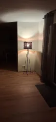 Eine moderne Stehlampe steht in einem hellen Raum. Das Wohnzimmer hat einen gemütlichen Holzfußboden und sanfte Beleuchtung.