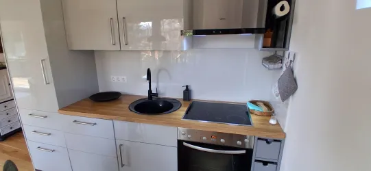 Eine moderne Küche mit hellen Schränken und einer Holzarbeitsplatte. Der Herd und die Spüle sind gut platziert, und es gibt Fensterlicht.