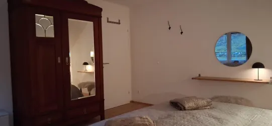 Ein gemütliches Schlafzimmer mit einem großen Kleiderschrank und einem runden Spiegel. Sanfte Beleuchtung schafft eine entspannte Atmosphäre.