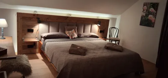 Ein gemütliches Schlafzimmer mit einem großen Bett und sanfter Beleuchtung. Die warme Holzverkleidung verleiht dem Raum eine einladende Atmosphäre.