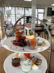 Ein schön dekorierter Dessertteller mit verschiedenen kleinen Gläsern und Leckereien. Oben befinden sich Obst und süße Snacks, während unten Cremes und Aufstriche arrangiert sind.