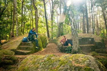 Wanderer bei der Rast am steinernen Kanapée im Pfälzerwald