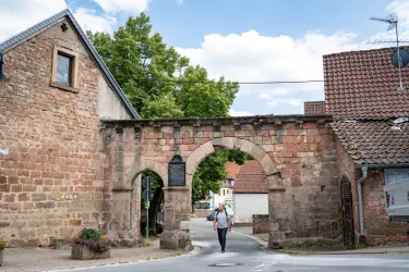 Wanderer läuft unter Torbogen des Augustiner Klosters Höningen