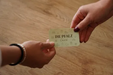 Nahaufnahme zweier Hände, die eine Pfalz-Card überreichen.