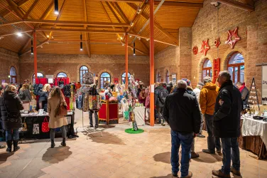 Menschen besuchen einen Weihnachtsmarkt in einem alten Gebäude.