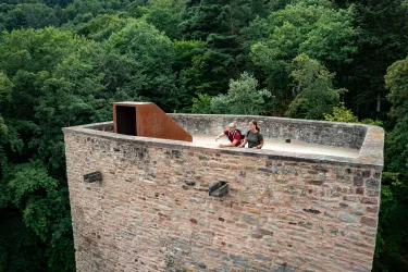 Zwei Personen stehen auf einem Turm der Burg Alt-Wolfstein im Lautertal am Pfälzer Höhenweg und bestaunen die Aussicht.