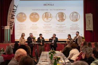 Sechs Personen stehen bei einer Podiumsdiskussion des Tourismustages Pfalz vor der Bühne.